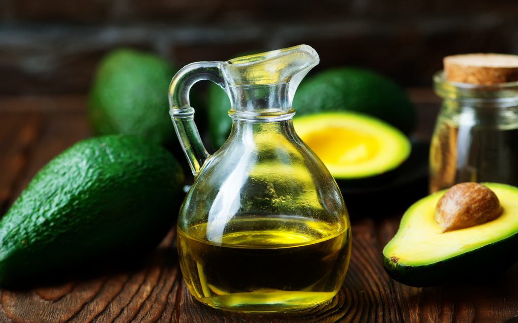avocado oil in a cute little bottle with some fresh avocados