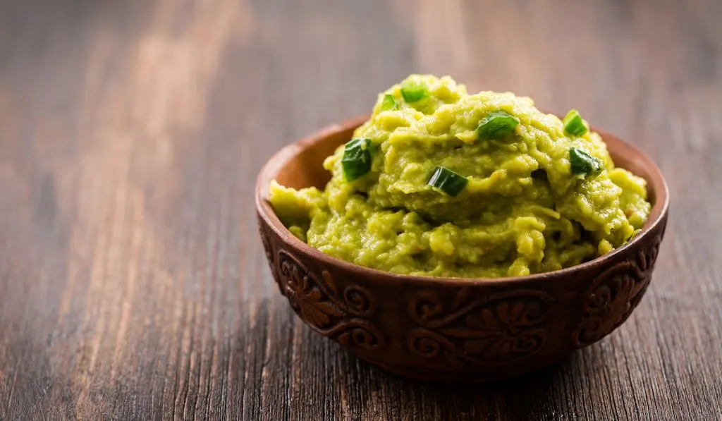 guacamole in a brown bowl on the table